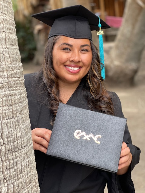female graduate in cap and gown holding her diploma