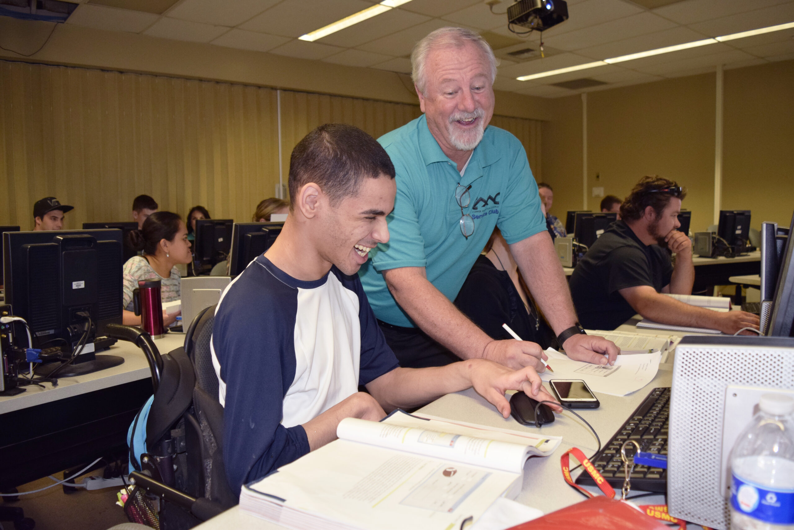 professor laughing with a student at their desk