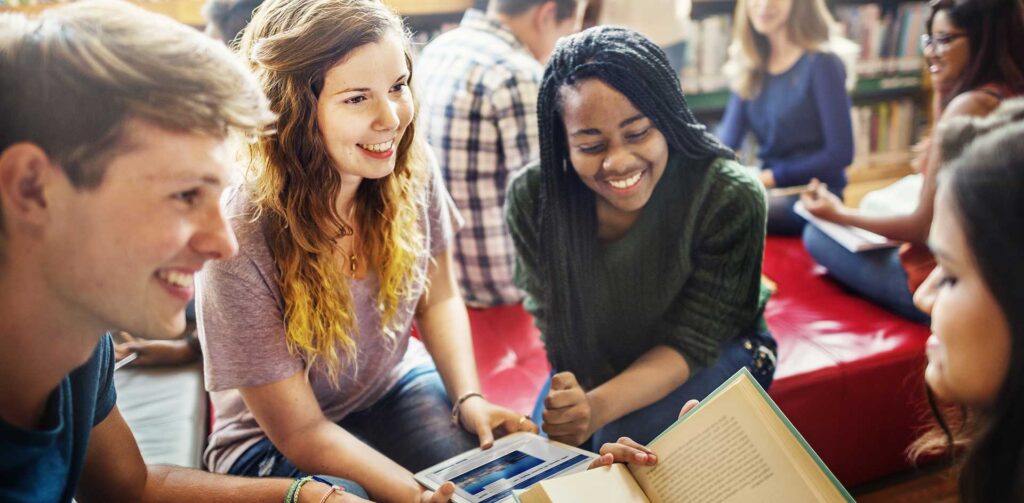 Group of students sitting together smiling. Credit: rawpixel.com