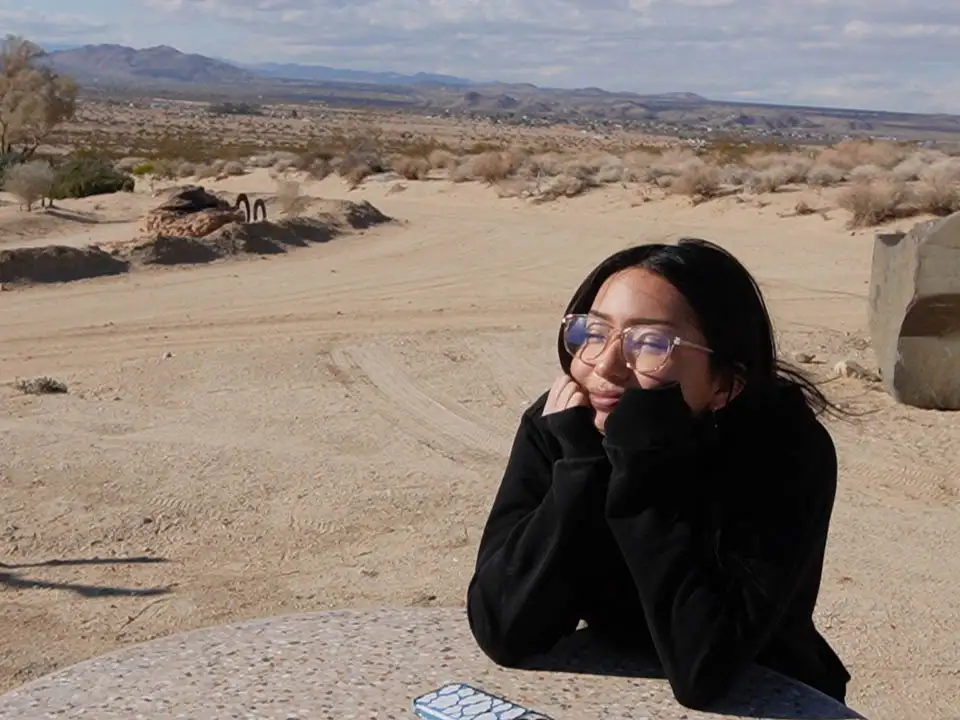 student sitting at a table in the desert/dirt area on campus