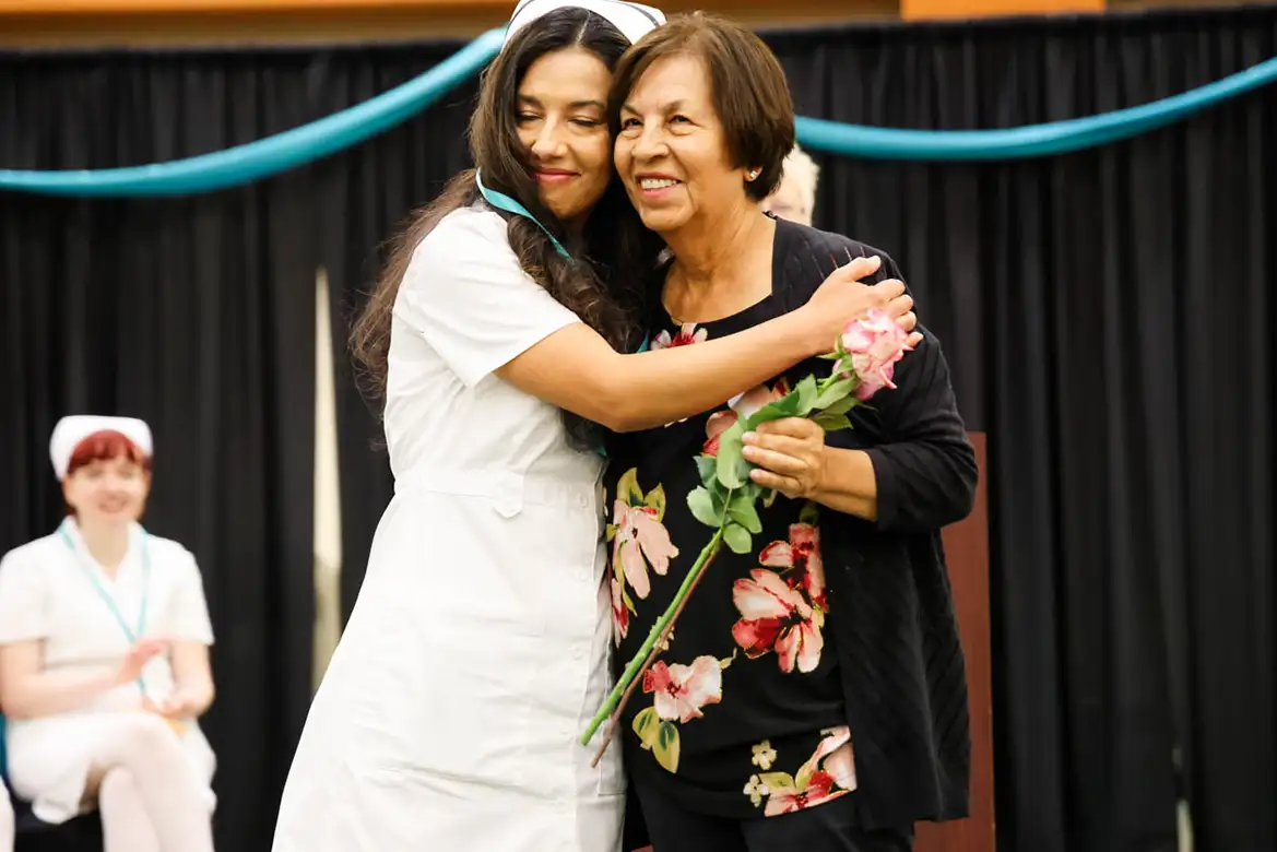 nursing student graduate hugging her mother on the stage