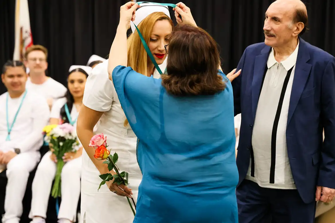 nursing student graduate's mother puts her ribbon on during the commencement ceremony