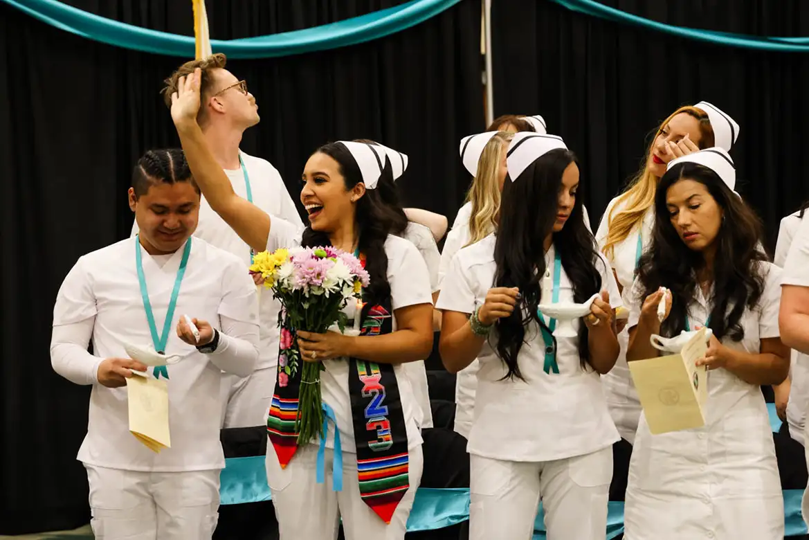 nursing student graduates waving and smiling to their families at the commencement ceremony