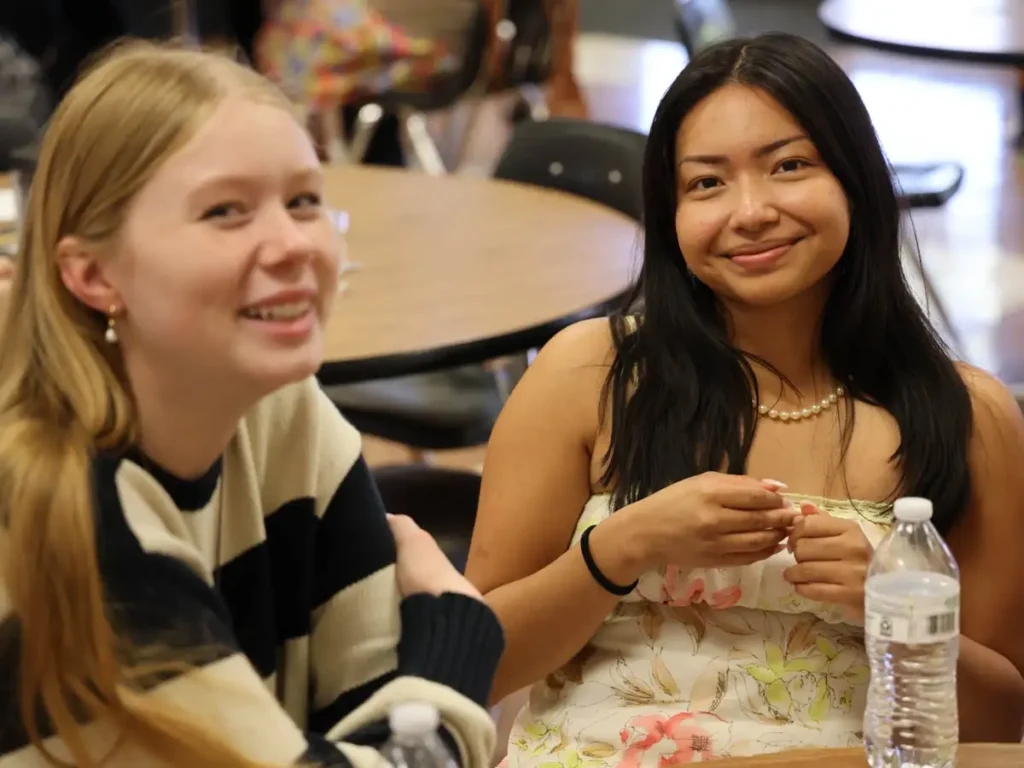 two students sitting at a table smiling