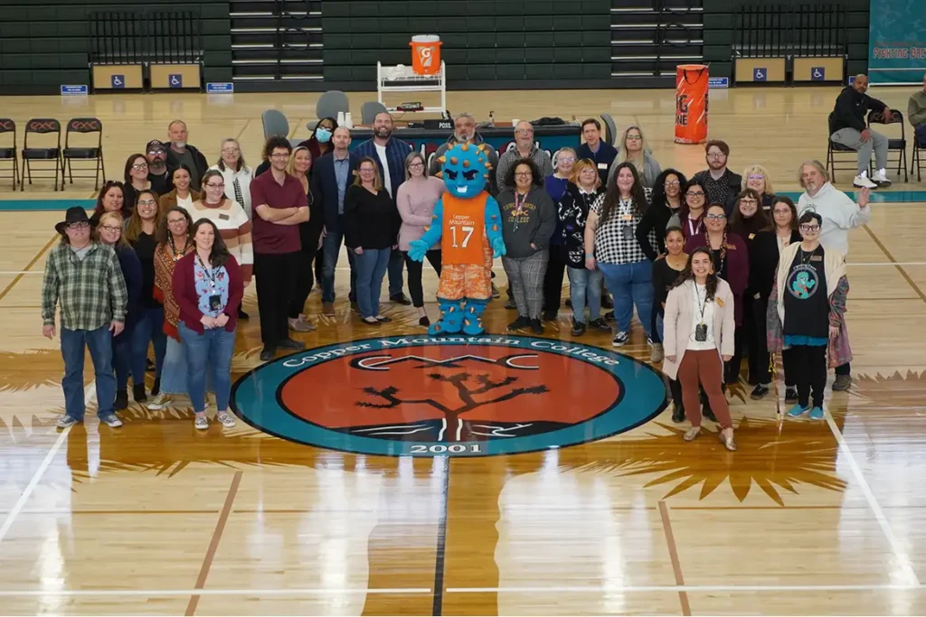 faculty members gathered together in the gym around the fighting cacti mascot