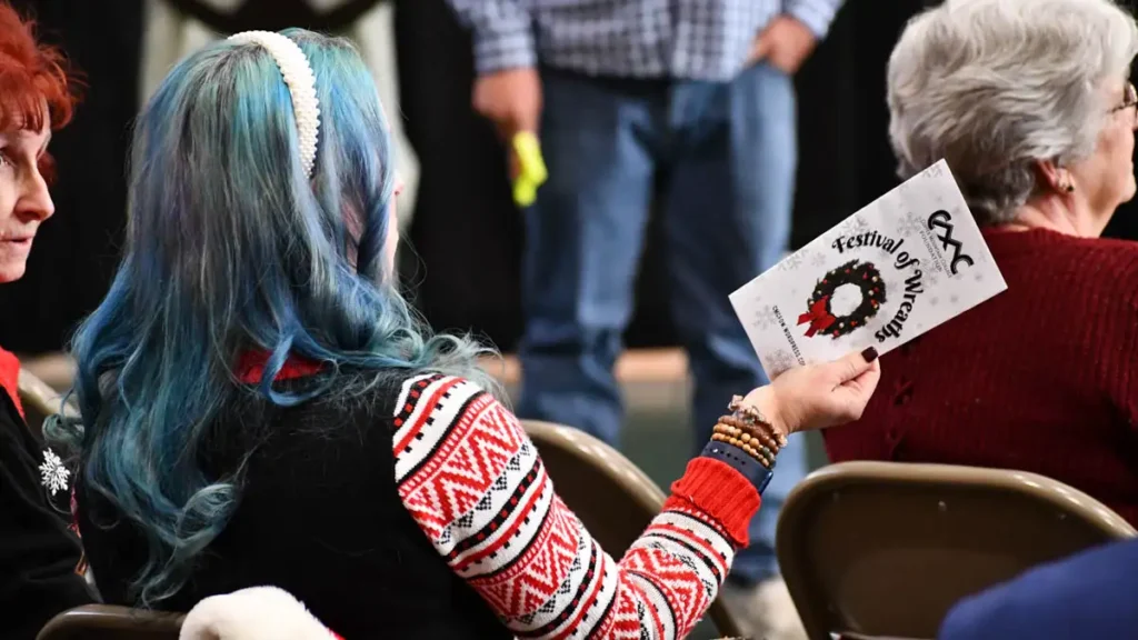woman holding a CMC Festival of Wreaths pamphlet