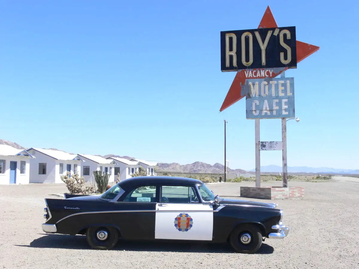 an classic police car sitting in front of Roy's motel cafe